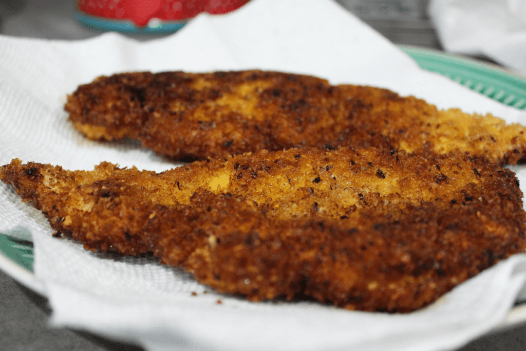 fried golden brown chicken just out of the skillet on a plate with paper towels