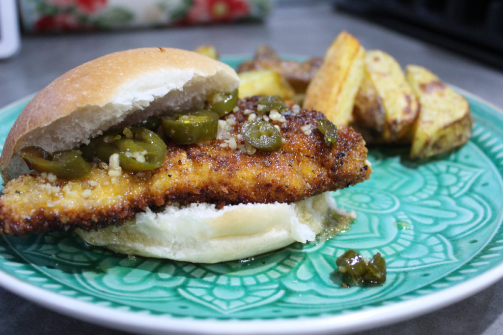 Fried Chicken sandwich with jalapeno honey sauce and potato wedges on the side